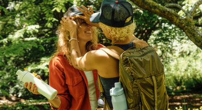 Two people in a forrest holding MiiR Wide Mouth Bottles