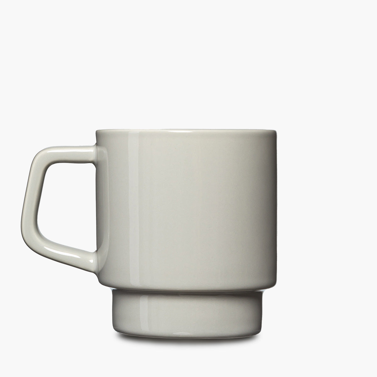 A minimalist ceramic mug with a wide handle and a tiered base, shown in a light gray color.