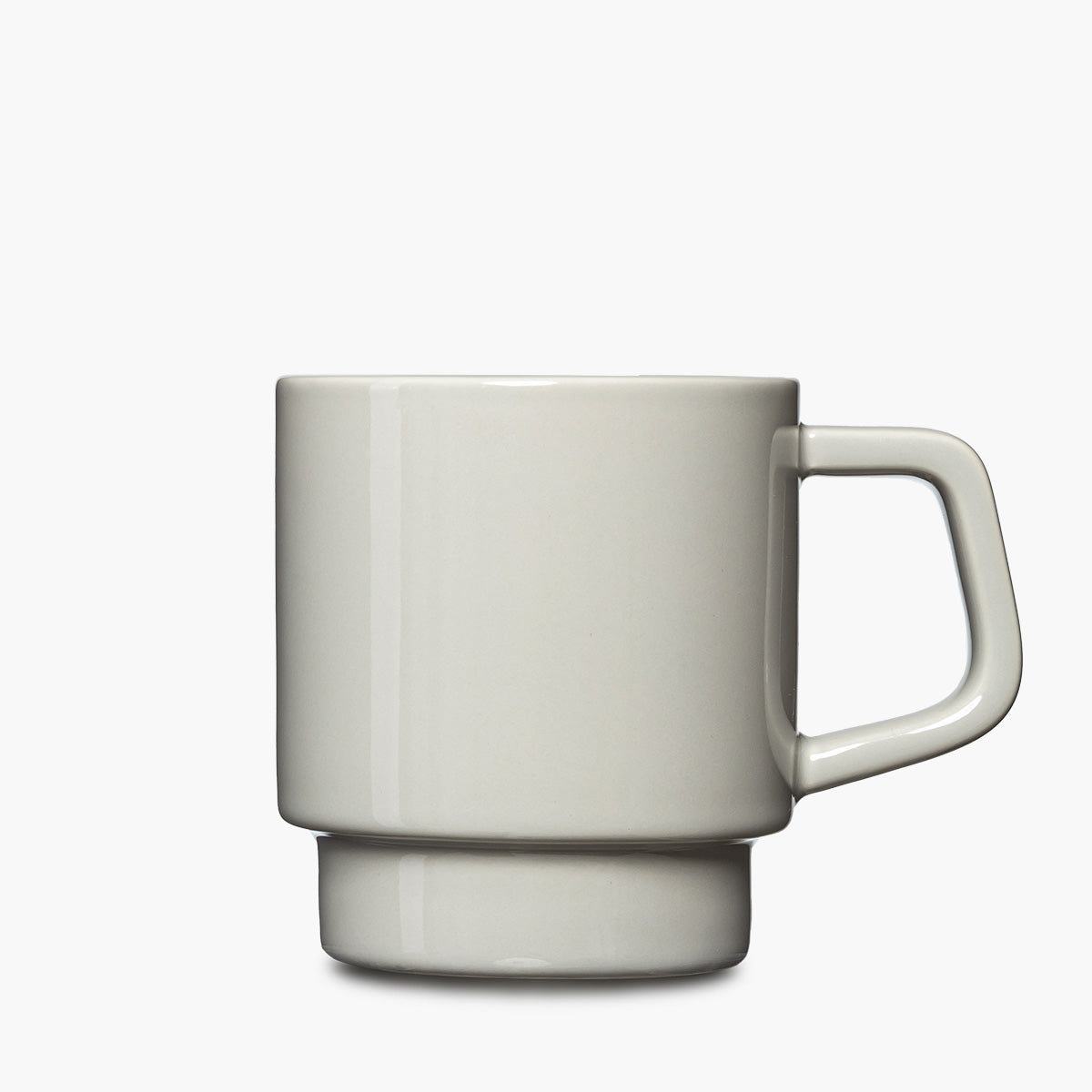 A minimalist ceramic mug with a thick, geometric handle and a matching ridged base, shown in a light gray color on a clean white background.