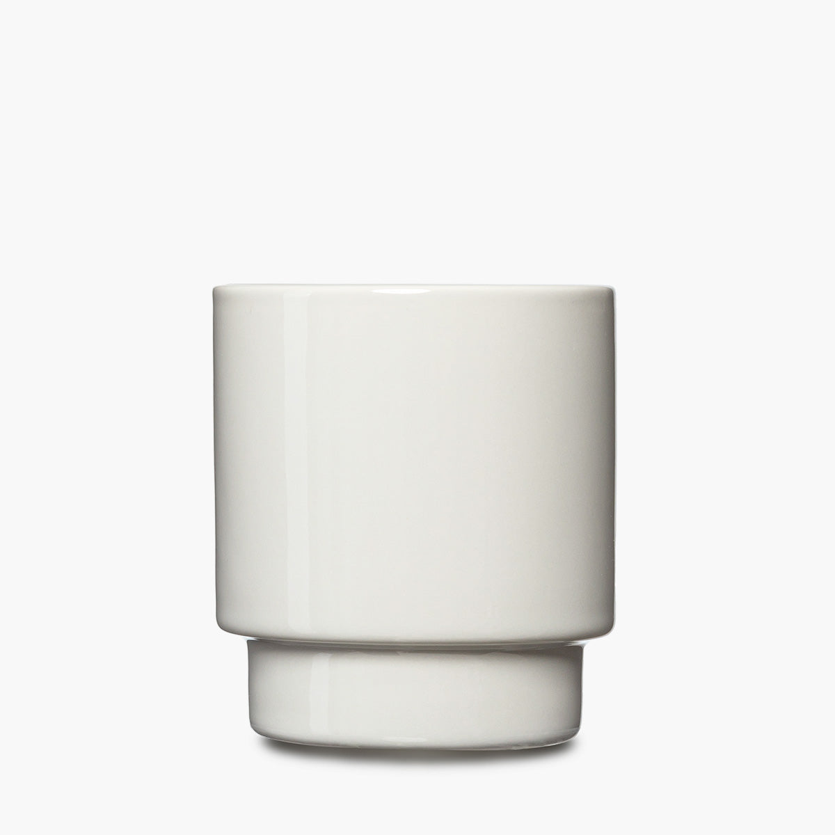 A minimalist white ceramic tumbler with a wide cylindrical body and a stacked, tiered base.