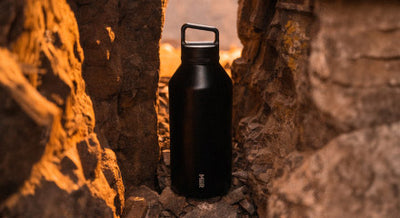 The 64oz Wide Mouth Bottle in between rocks on either side of it